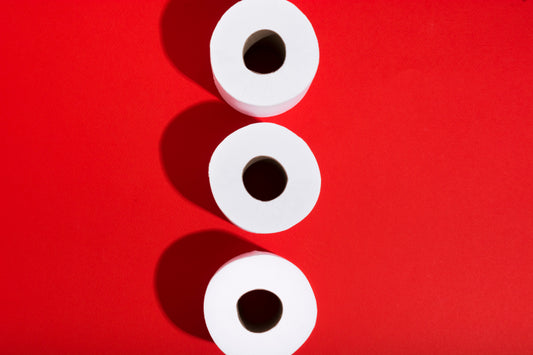 Top view of three white toilet paper rolls on a red background.